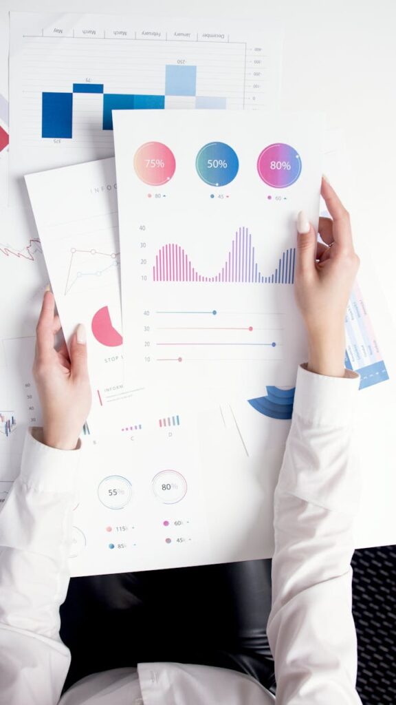 Services Close-up of hands analyzing colorful business data reports in an office setting.